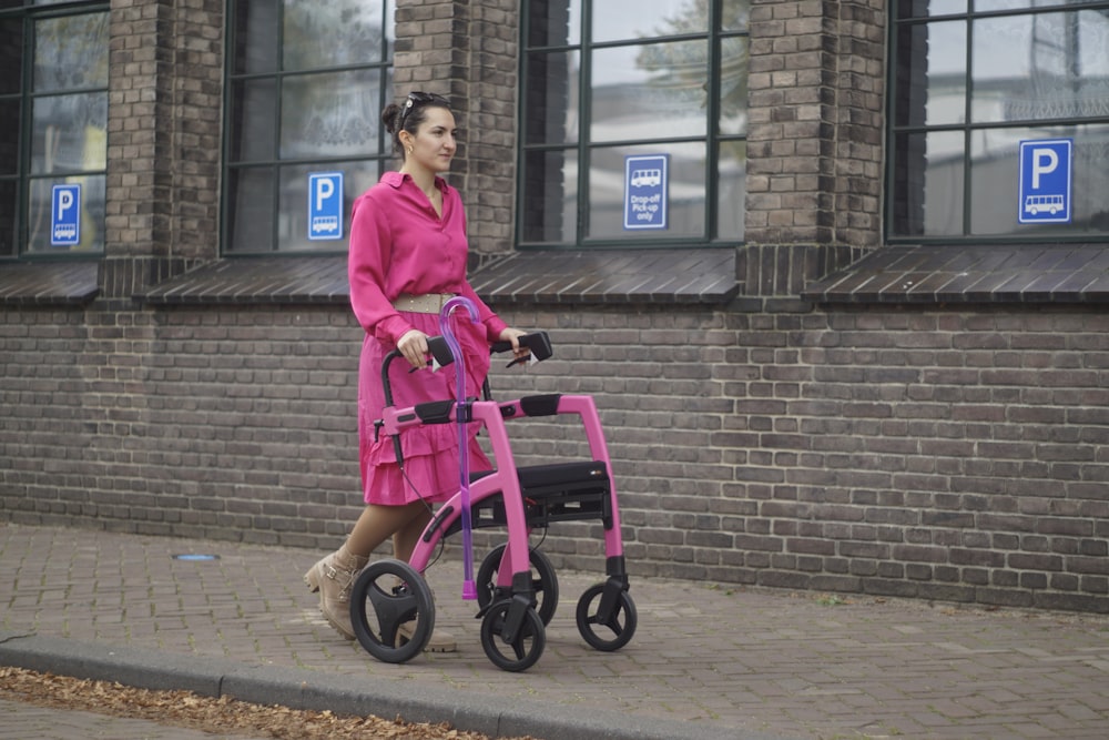 a woman in a pink dress pushing a pink walker