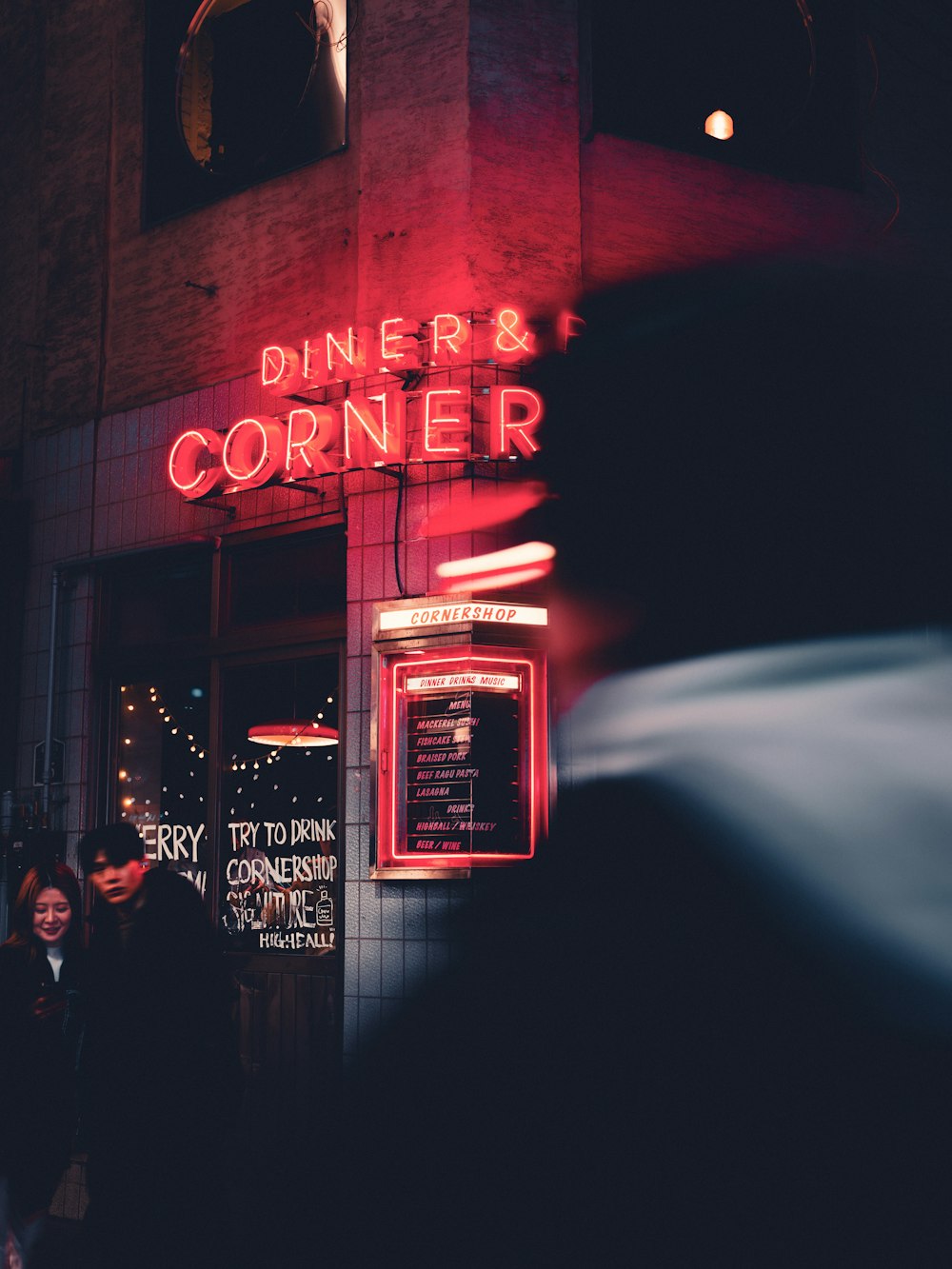 a person standing outside of a restaurant at night