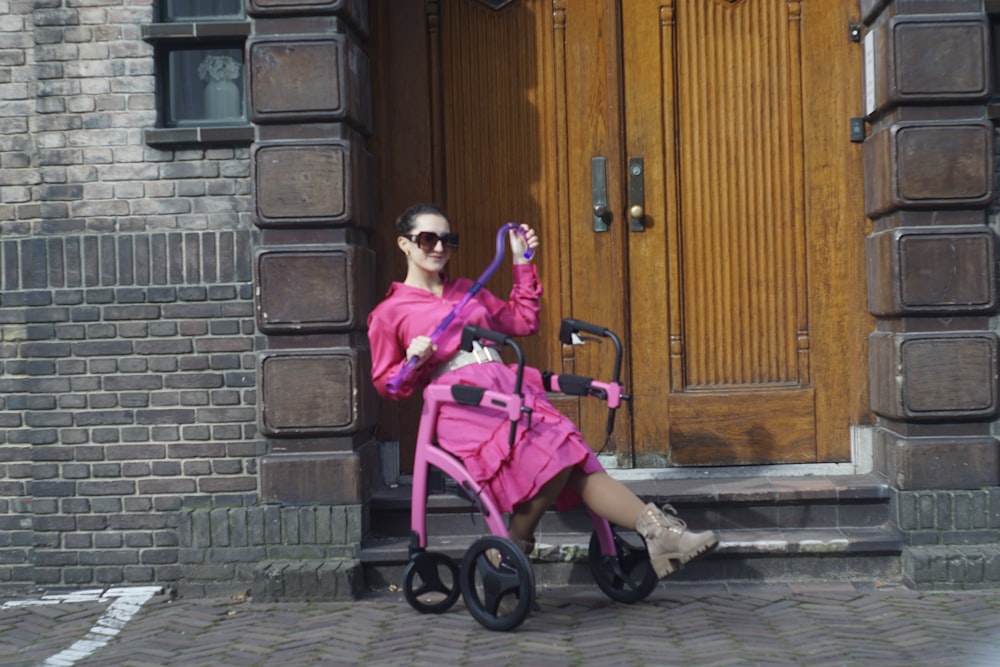 a woman in a pink dress sitting on a pink stroller