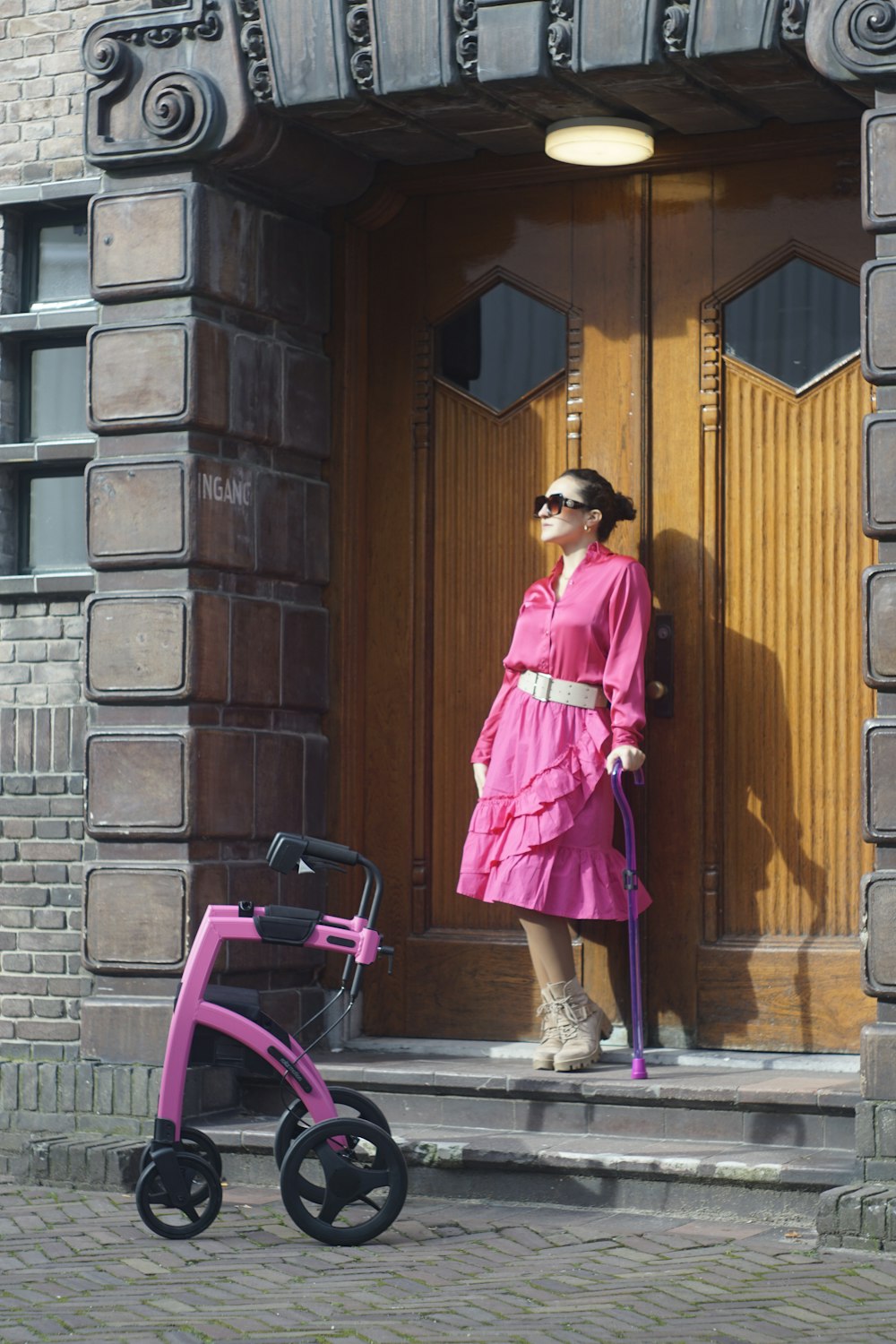 a woman in a pink dress is standing on the steps of a building