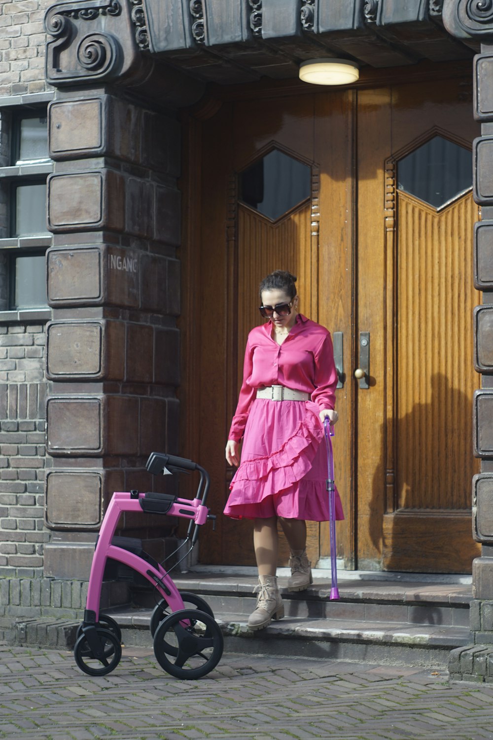 a woman in a pink dress is holding a cane