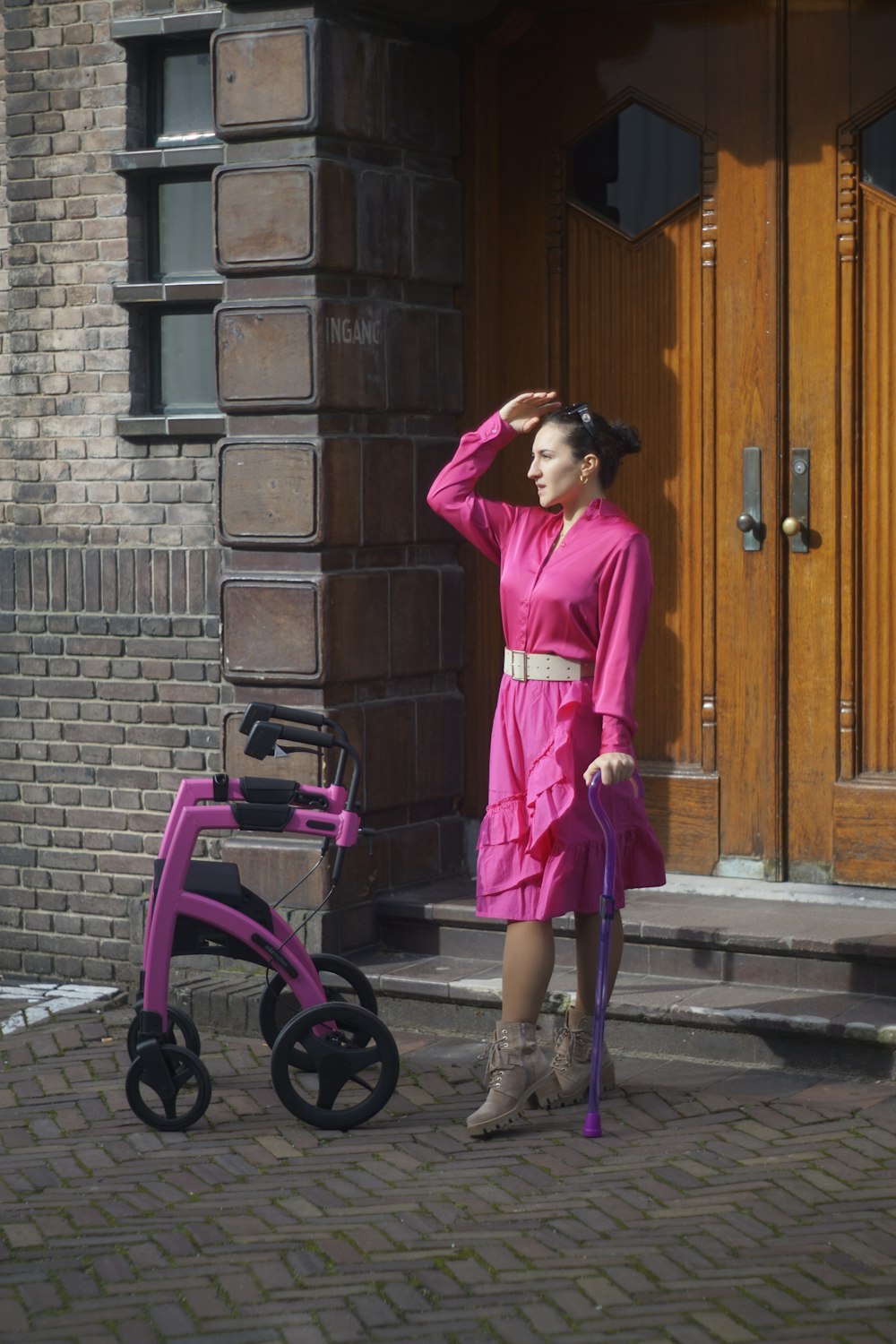 a woman in a pink dress standing next to a pink stroller