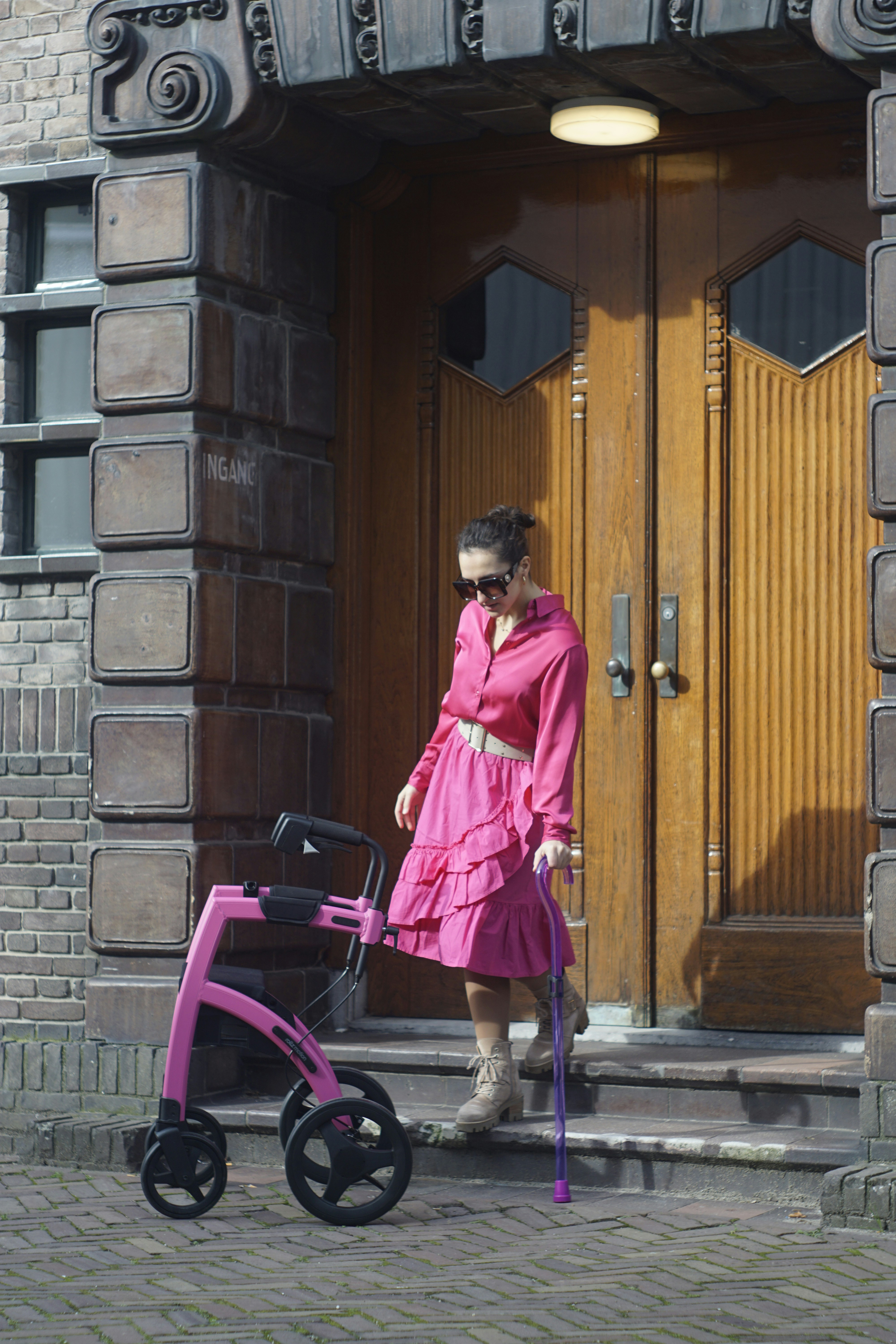 a woman in a pink dress is pulling a stroller