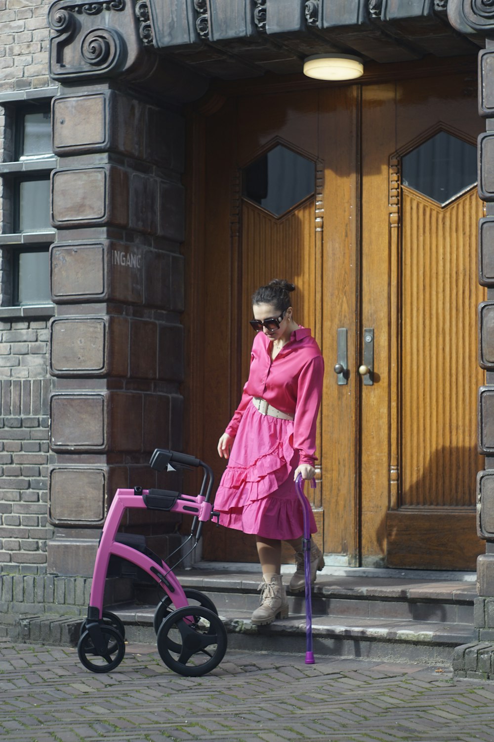 a woman in a pink dress is pulling a stroller