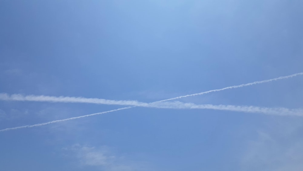 two airplanes flying in the sky with contrails in the sky