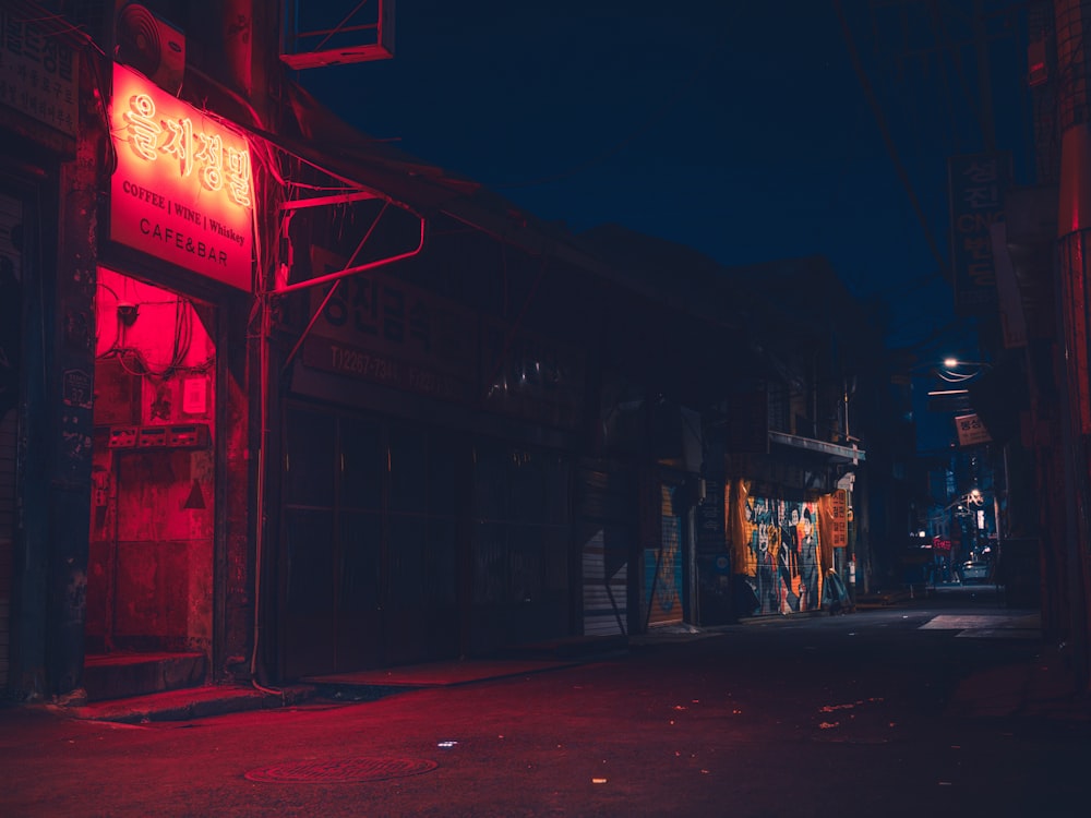 a dark street at night with a red neon sign