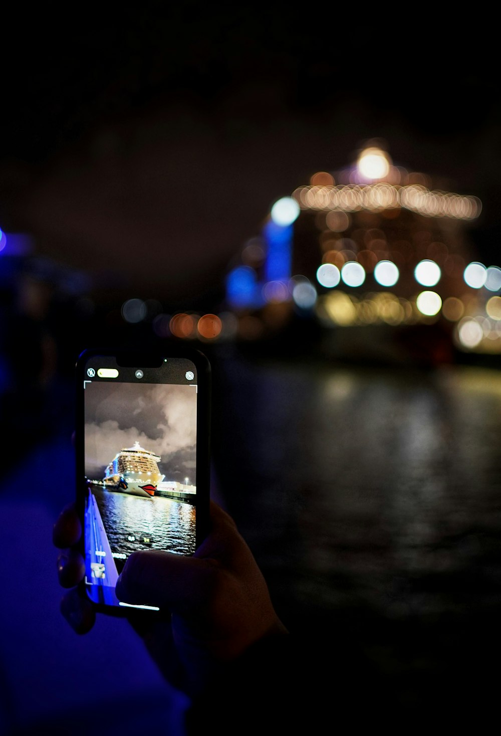 a person taking a picture of a boat at night