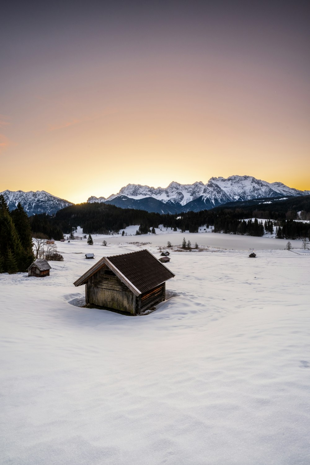 a small cabin in the middle of a snowy field