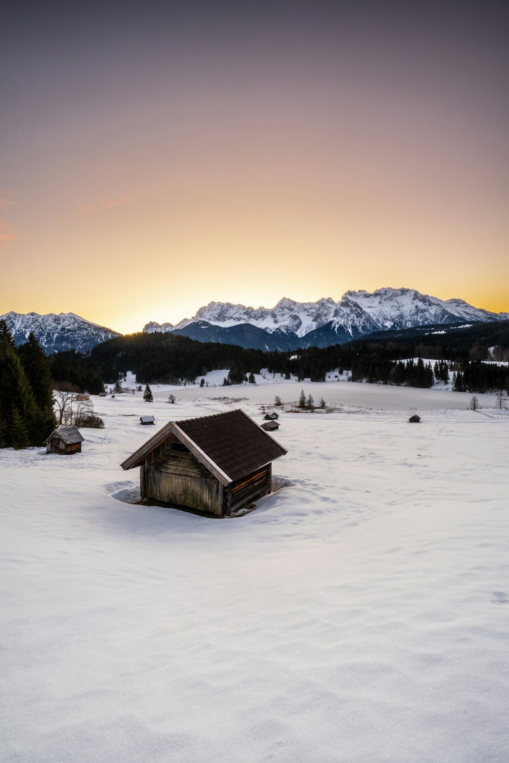 una pequeña cabaña en medio de un campo nevado
