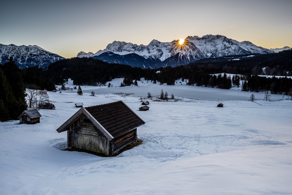 a small cabin in the middle of a snowy field