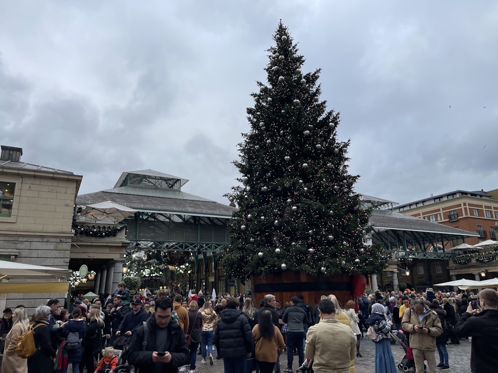 a group of people standing around a christmas tree