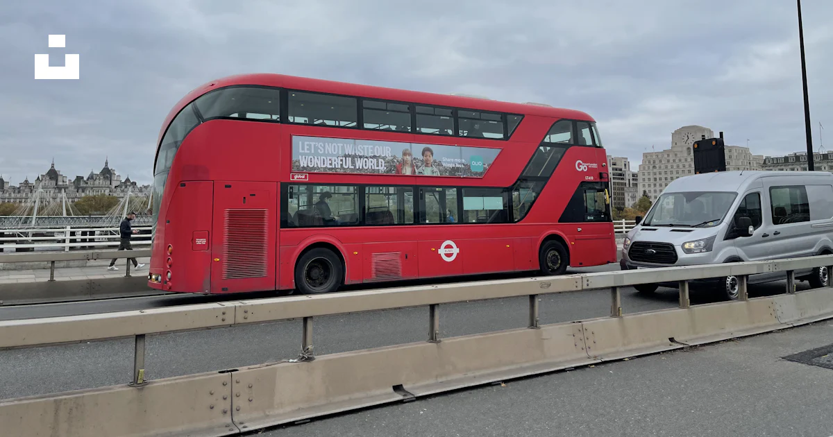 A red double decker bus driving down a street photo – Free Road Image ...