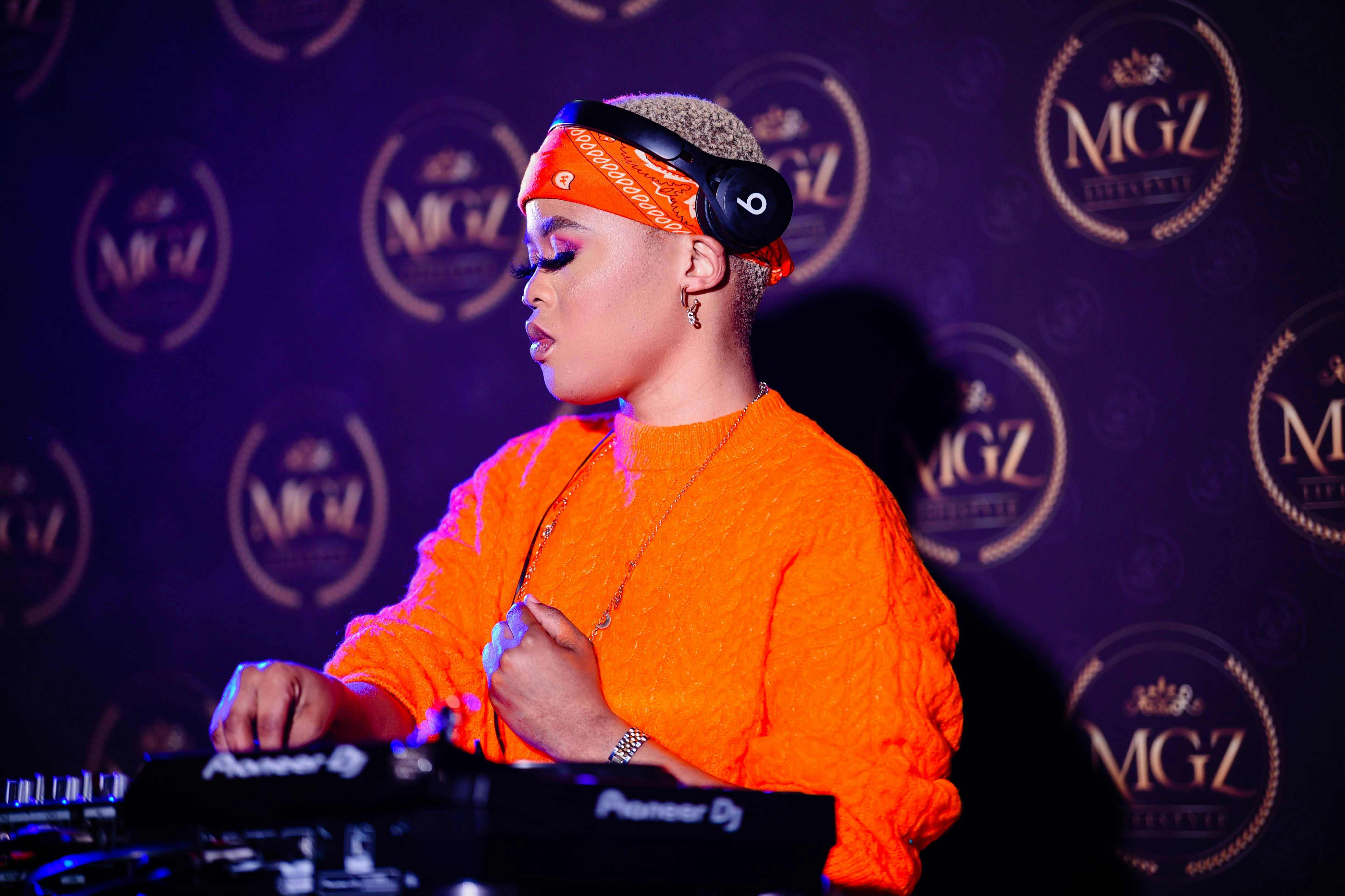 a woman in an orange shirt and headband at a dj booth