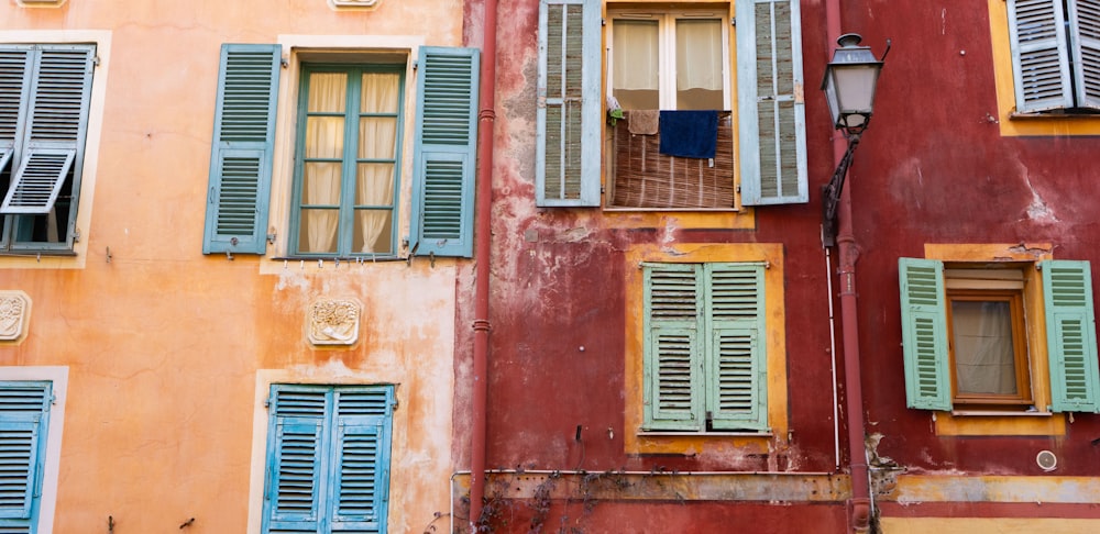 a row of windows with green shutters and blue shutters