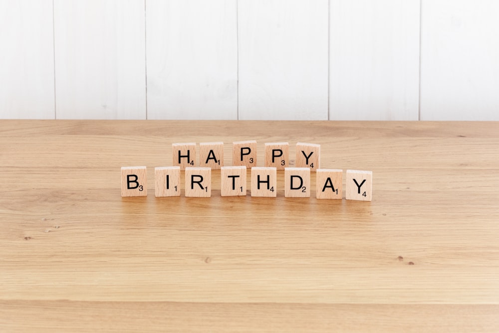 a wooden block spelling happy birthday on a table