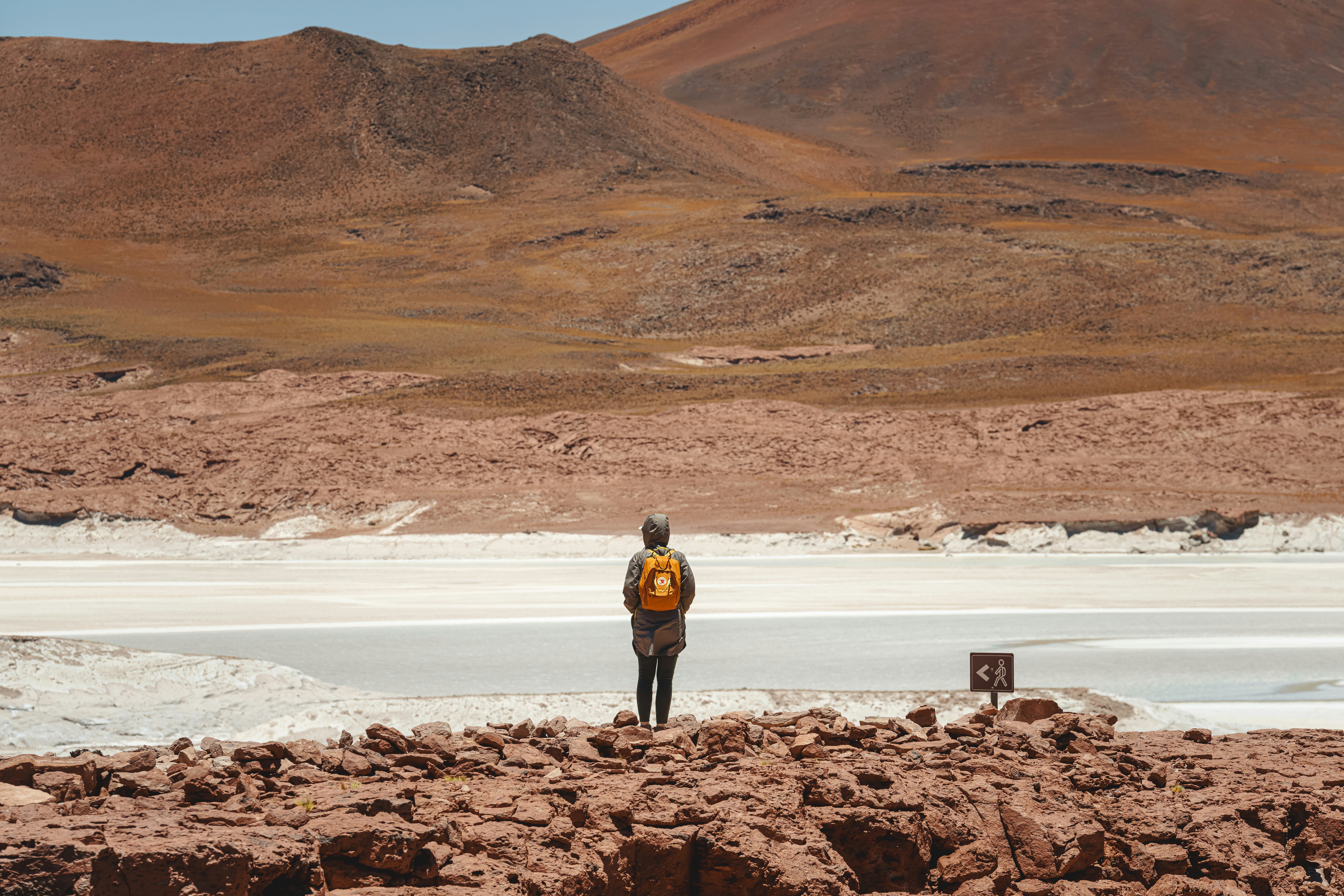 a person standing on a rocky area with a mountain in the background