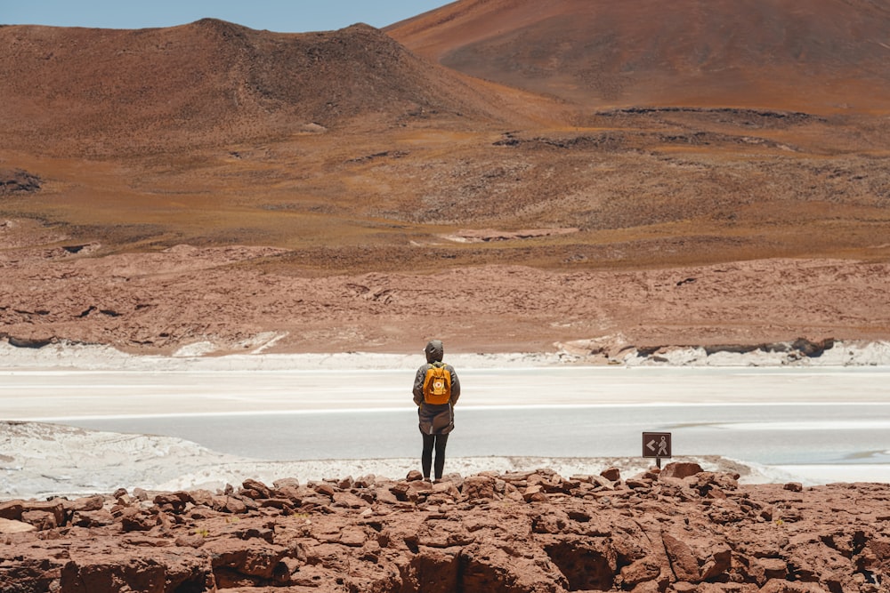 a person standing on a rocky area with a mountain in the background