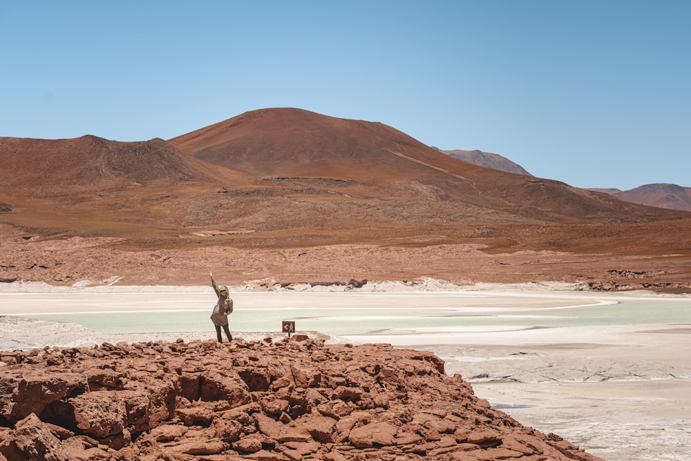 a person standing on a rocky outcropping with a mountain in the background