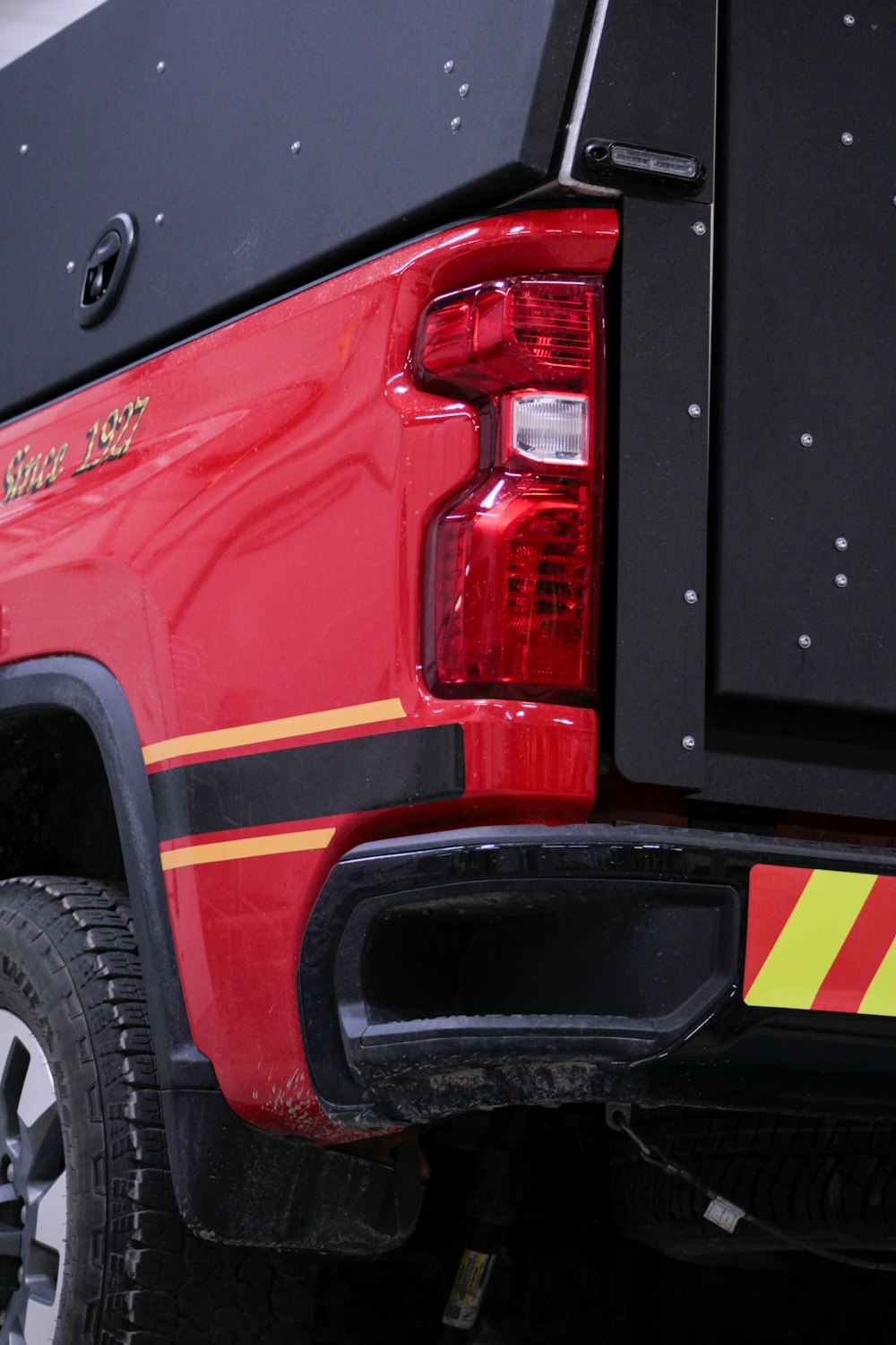 the back end of a red truck with a yellow stripe