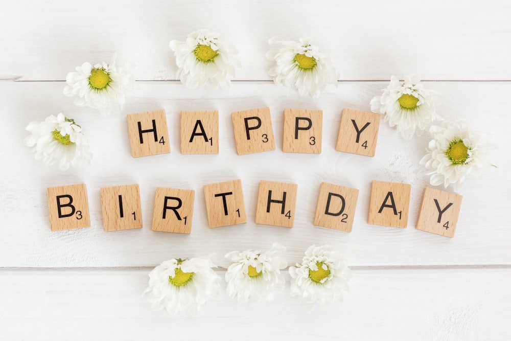 a happy birthday spelled with scrabbles and daisies