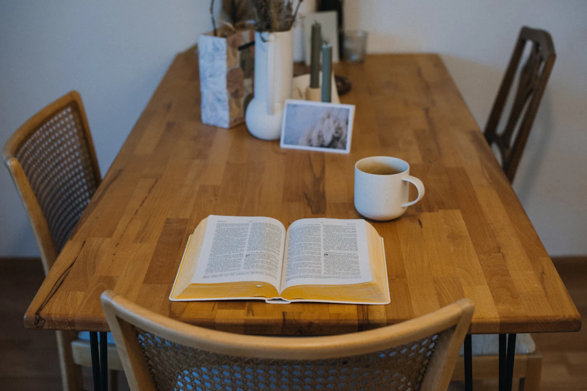 Open Bible on wooden table with coffee