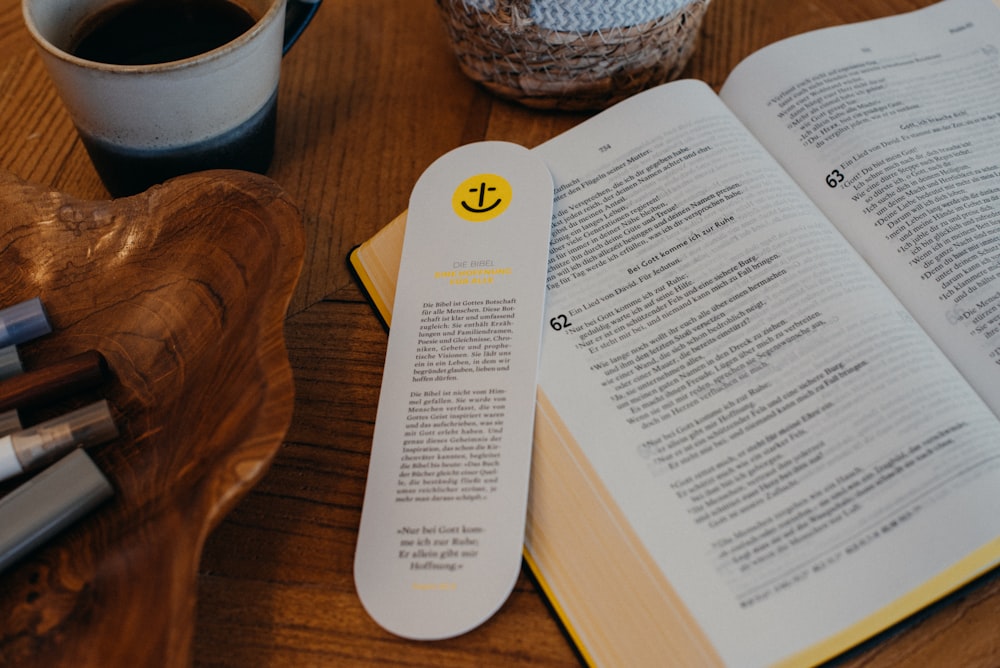 an open book on a table next to a cup of coffee