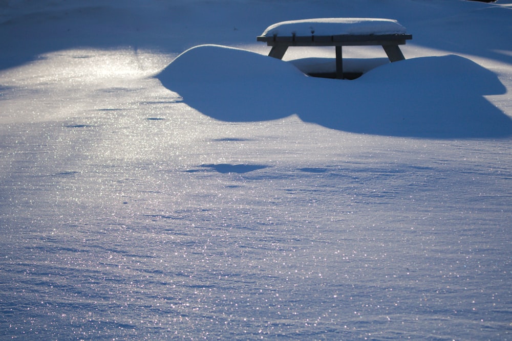 a snow covered park bench sitting in the middle of a field