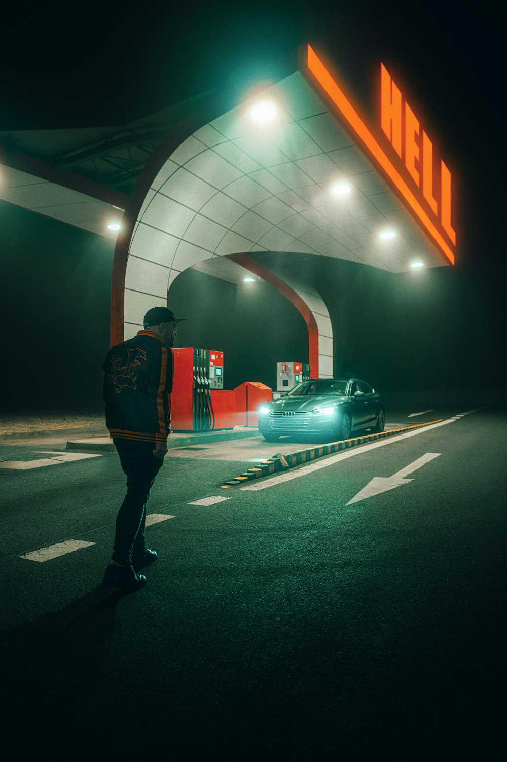 a man standing in front of a gas station at night