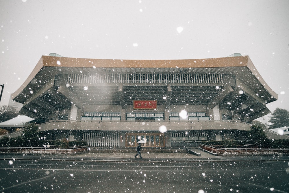 a person walking in front of a building in the snow