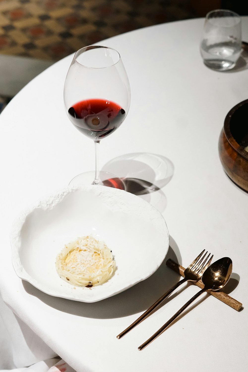 a white table topped with a plate of food and a glass of wine