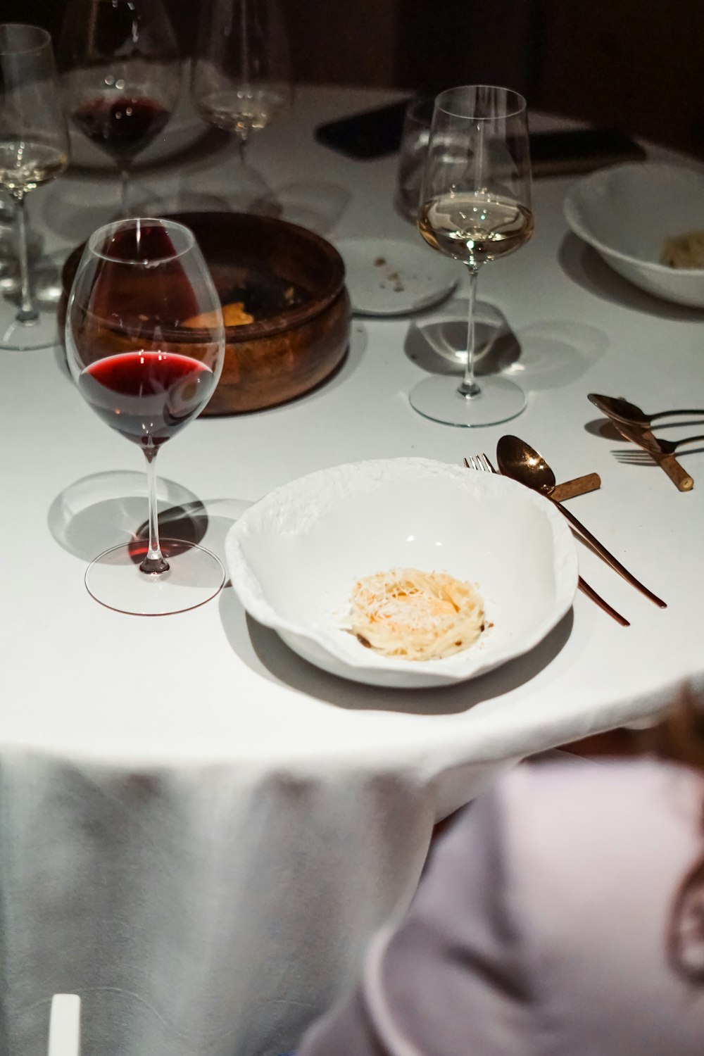 a white table topped with plates and glasses of wine