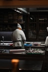 a couple of men standing in a kitchen preparing food