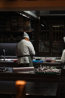 a couple of men standing in a kitchen preparing food