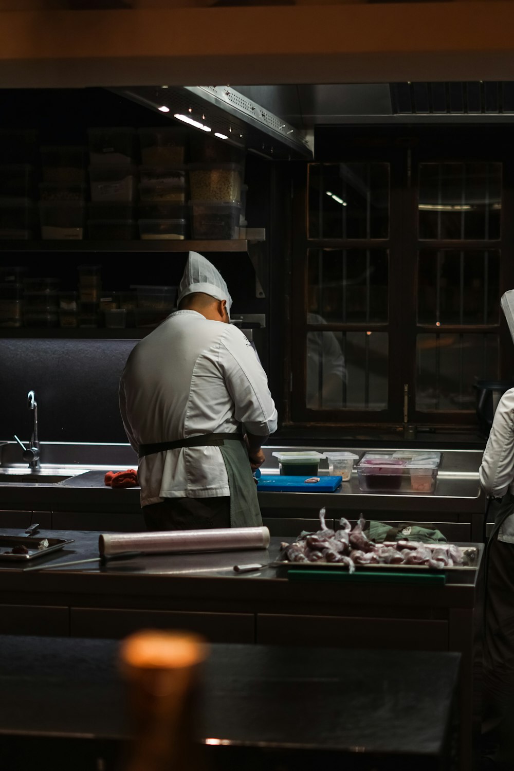 a couple of men standing in a kitchen preparing food