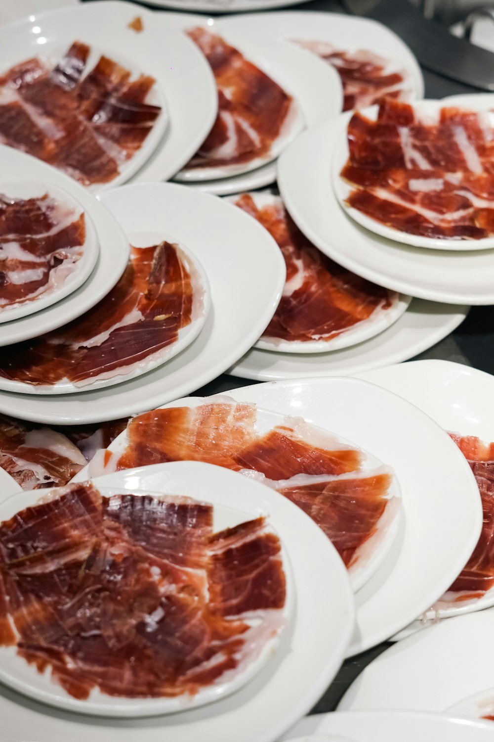 a table topped with white plates covered in bacon