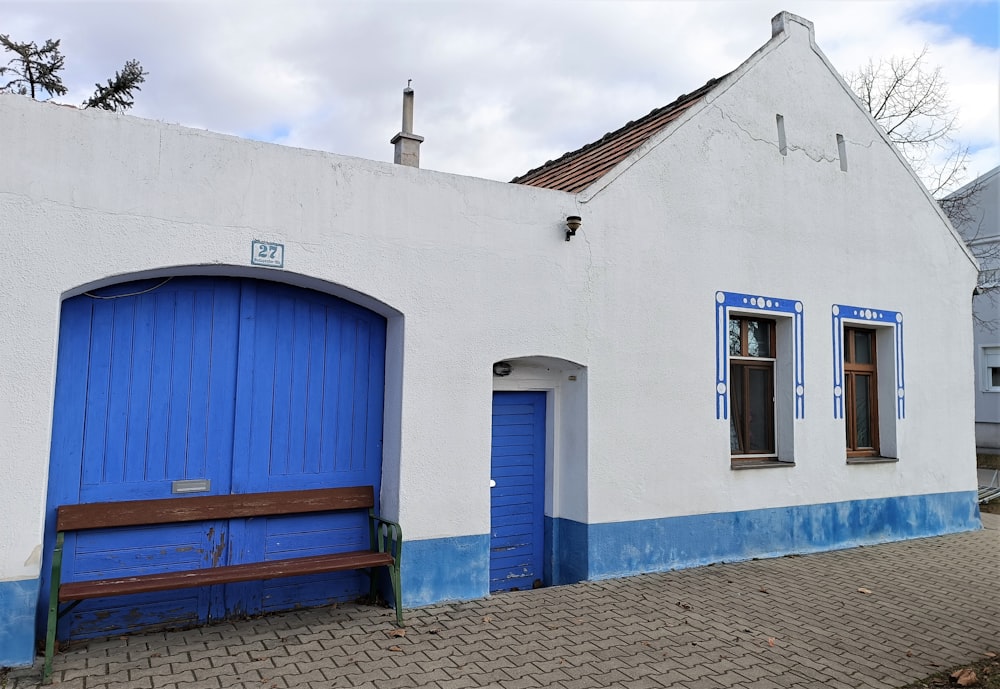 a white building with blue doors and a bench in front of it