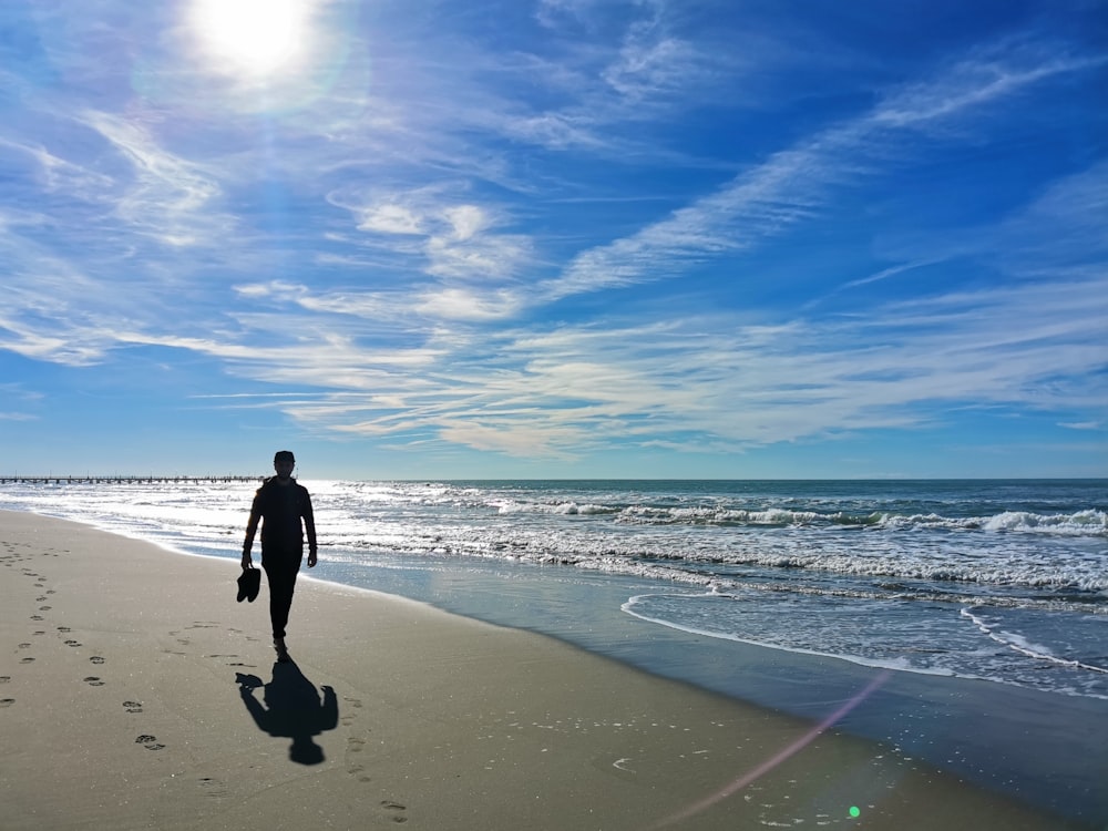 a man walking along a beach next to the ocean