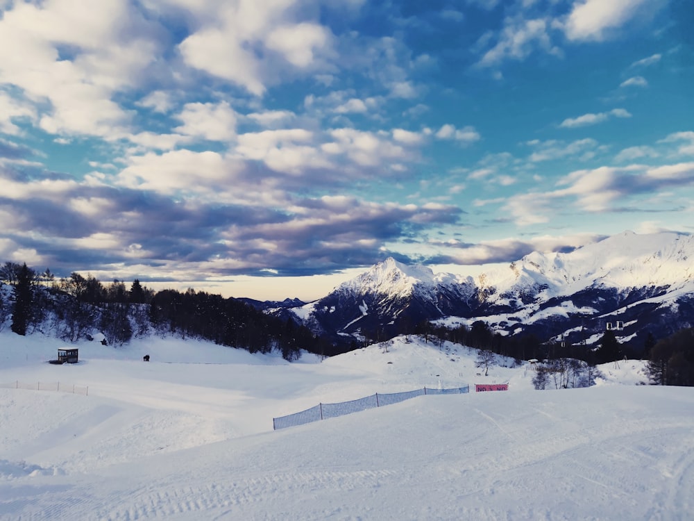 a snow covered ski slope with mountains in the background