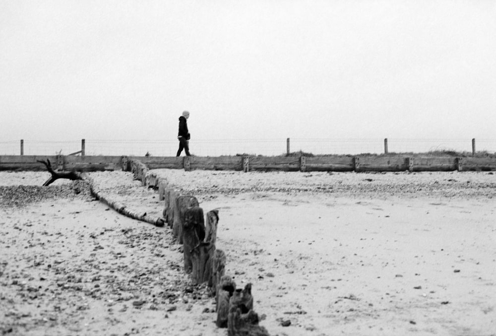 a black and white photo of a person walking in the snow