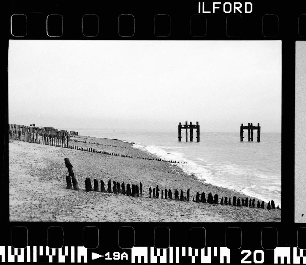 a black and white photo of a beach and pier