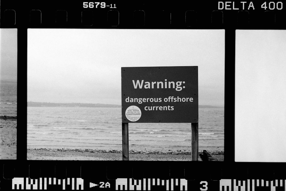 a black and white photo of a sign warning of dangerous offshore currents