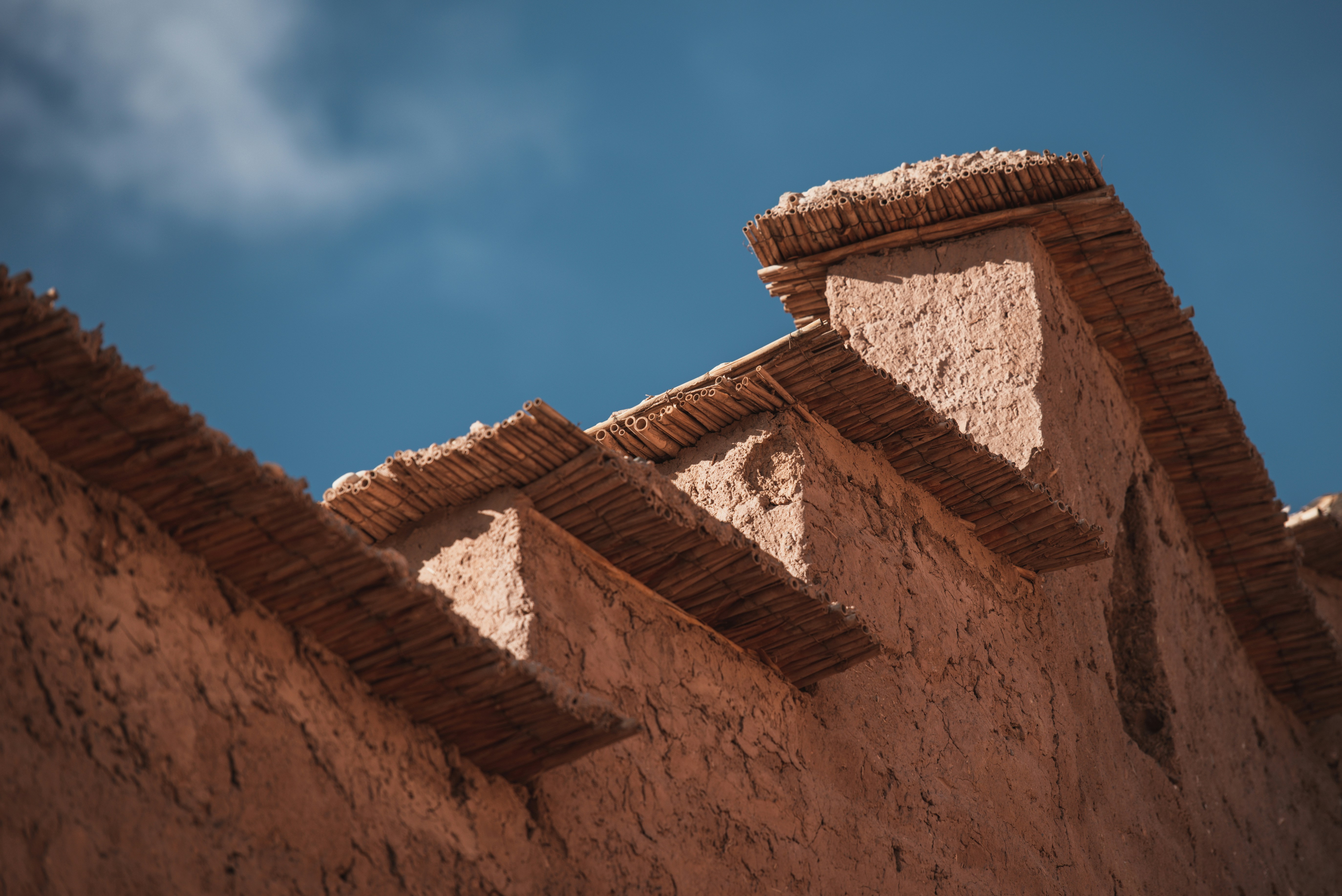 The roof of a adobe building with a blue sky in the background