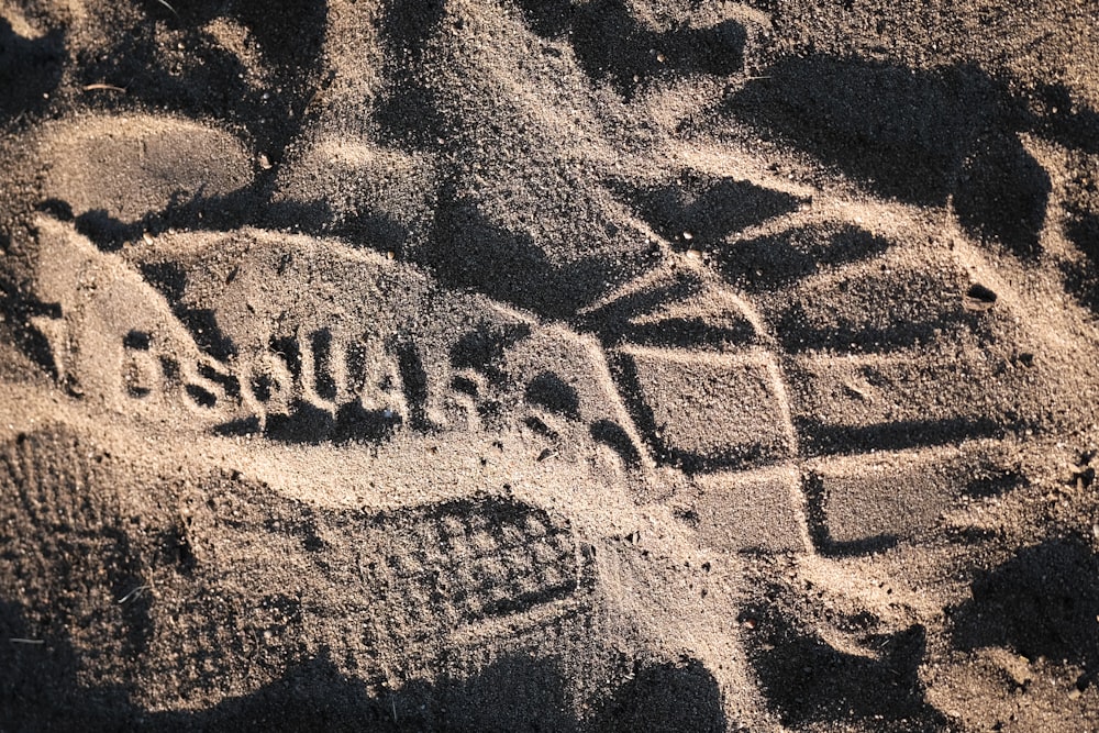 a close up of sand with a person's feet in the sand