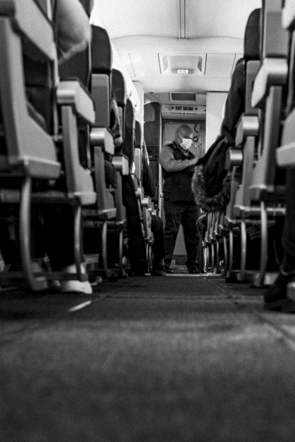 a black and white photo of a man standing on an airplane aisle