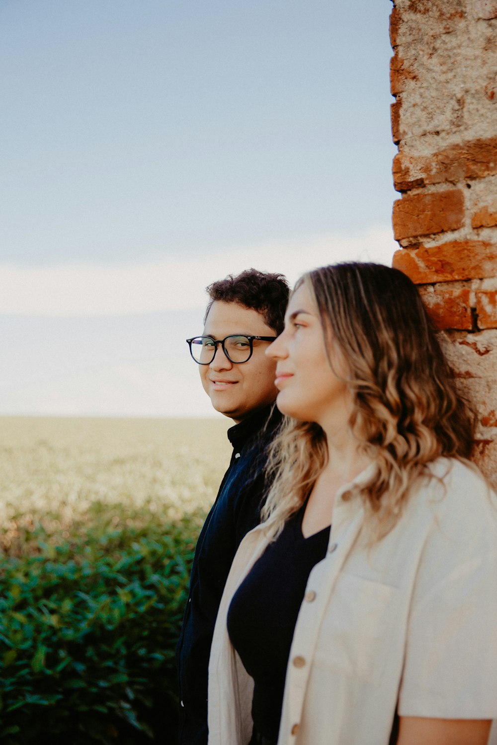 a man and a woman standing next to a brick wall