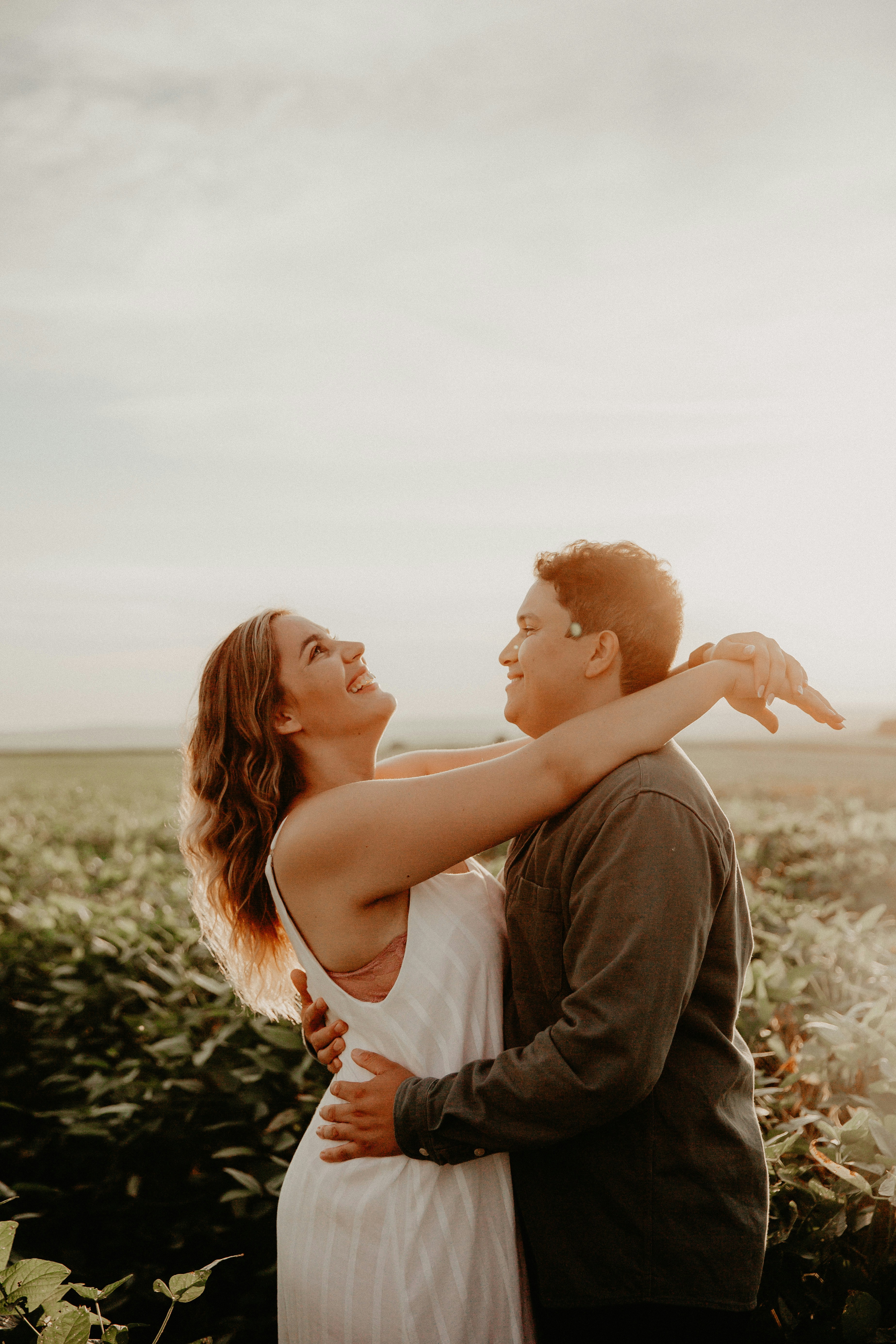 Two people laughing together outdoors, warm golden hour light, candid and joyful