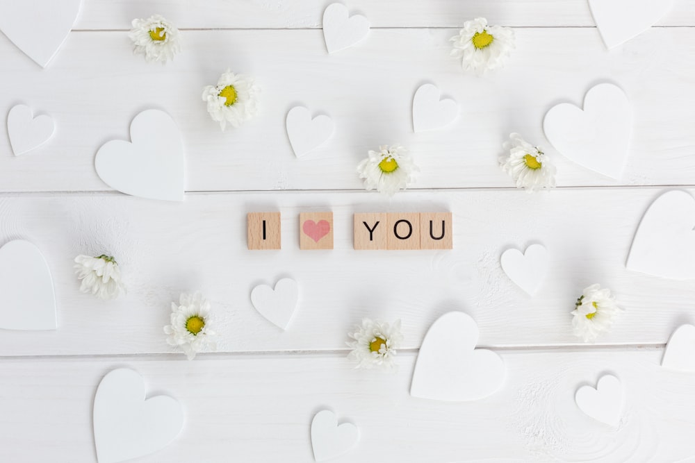 the word i love you spelled with scrabbles and daisies