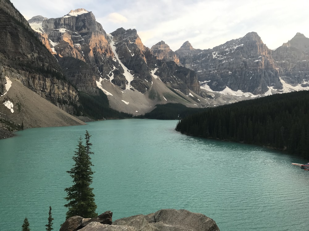 a lake surrounded by mountains with a boat in the water