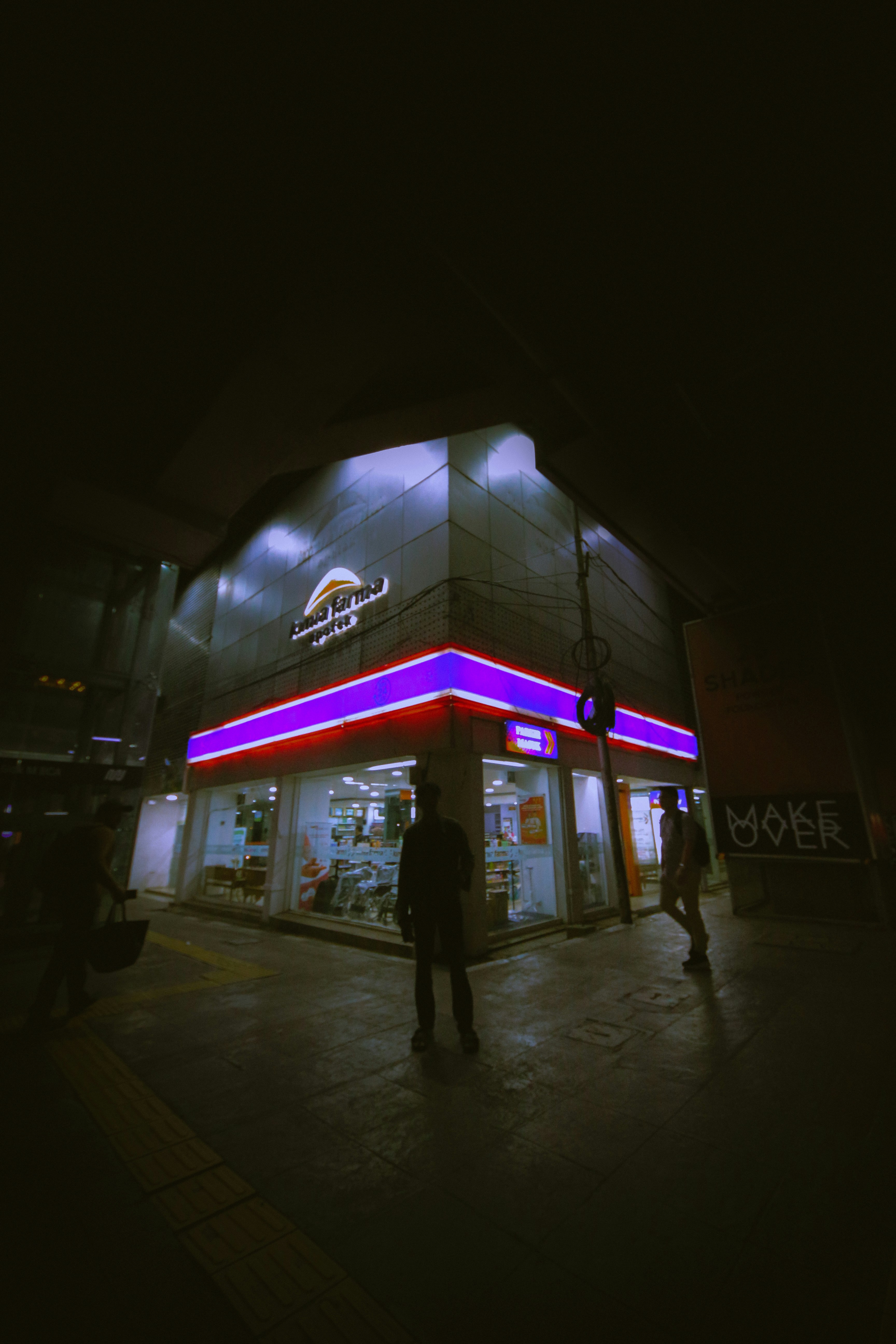 people are walking outside of a store at night