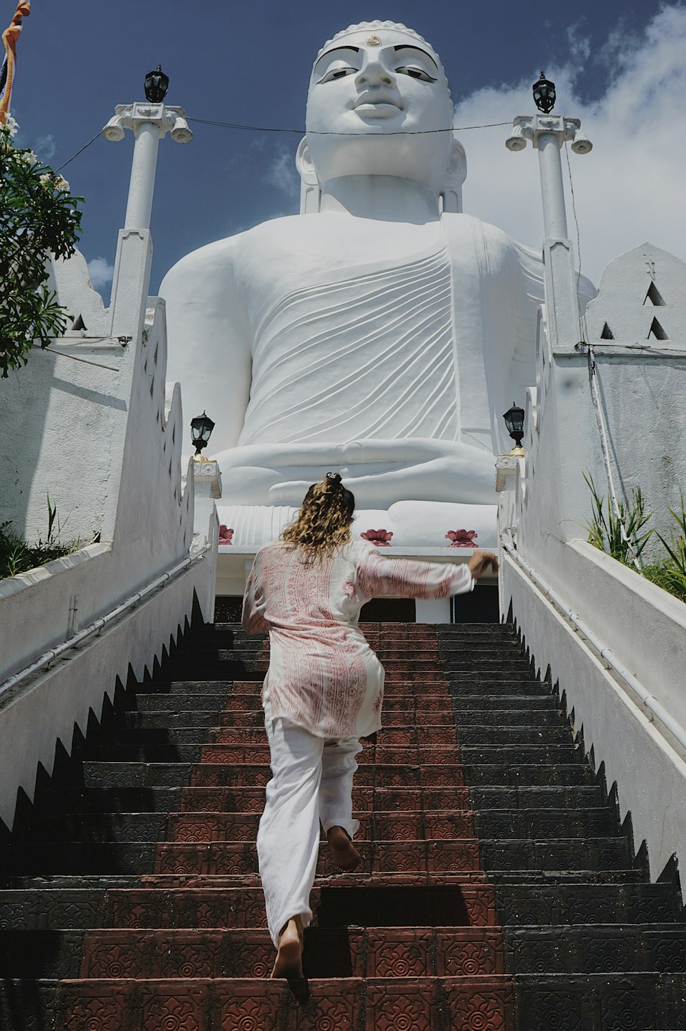 a woman walking down a flight of stairs towards a giant buddha statue